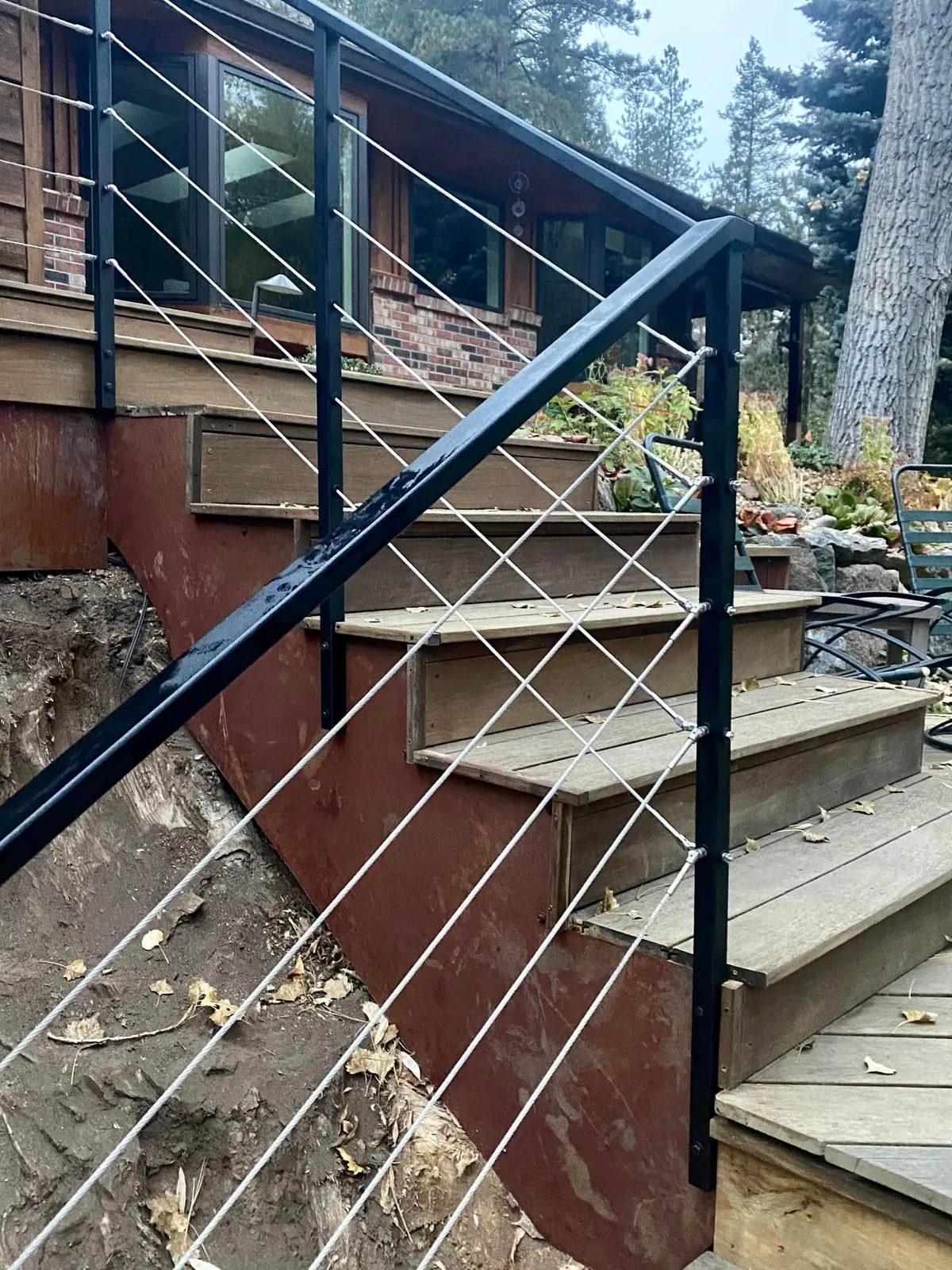 Black steel residential stair railing with stainless cable infill